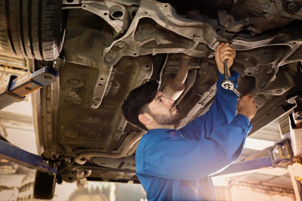 male underneath the car tightening cross member